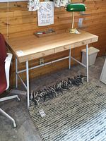 Front view of desk showing bamboo top, drawers, white metal legs and lamp