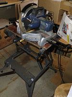Side angle view showing the miter saw mounted on the Workmate stand, highlighting the blade guard and saw base with angle markings.