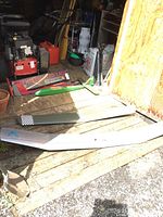 Photo of two wooden model airplane wings and Sophisticated Lady plane kit box on wooden flooring in open shed. Wings are separate and large sized.