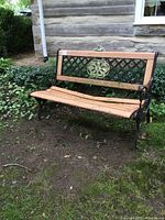 Front view of outdoor bench showing cast iron ends, lattice back with floral medallion, and aluminum seating boards.