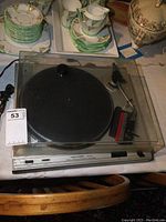 Front view of the record player with the dust cover closed, showing the platter and tonearm inside.