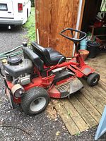 Left side view of red Snapper riding mower showing deck, engine and seat