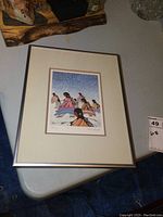 Framed print sitting on a table showing the entire frame and mat with print.