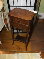 Full front view of the vintage wood stand showing two drawers and lower shelf on slender legs, placed on wooden floor.
