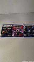 Front view of three PS5 game cases showing cover art for Spider-Man Miles Morales, Guardians of the Galaxy, and NHL 22