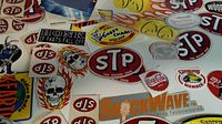 Photo showing various vintage decal stickers including STP logos, skull designs, and others on a flat surface.