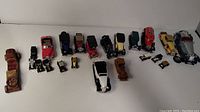 Full view of multiple Model T toy cars arranged in a line showing different colors and sizes, some with missing parts.