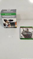 Overwatch Legendary Edition Xbox One game box and The Witcher 3 Wild Hunt Xbox One game case side by side.