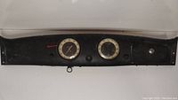 Front view of the vintage car dashboard showing two circular gauges and black metal frame.