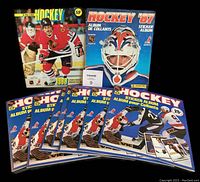 Photo showing the nine hockey sticker albums arranged with covers facing forward including Panini and O.P.C. editions from 1981 to 1989.