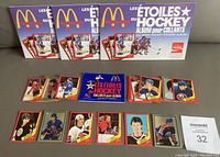 Photo of four hockey sticker albums with multiple stickers spread out in front, showing front covers and stickers together for lot overview.