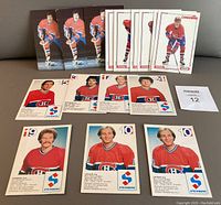 Eighteen Montreal Canadiens hockey player postcards laid out on a flat surface, front side shown. Top row includes 7 Larry Robinson cards from 1982/83 Steinberg series showing him in red Canadiens uniform. Next row includes 2 Guy Lafleur cards from the same Steinberg series. Remaining cards show Jean Hamel and other players from the 1984/85 and 1989/90 Kraft series respectively.