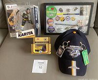 Full lot display showing Paul Kariya figurine in original box, Limited Edition Fleer Zamboni model unopened, framed pin/button/keychain set, and navy Predators hat with keychains attached.