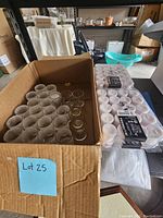 Box of clear glass candle holders with several packs of white tealight candles beside it