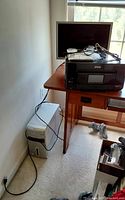 Epson black inkjet printer sitting on desk surface with power cords on top