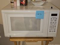 Front view of GE white microwave oven with label Lot 3