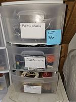 Photo of the storage container showing three drawers with labels: Plastic Wheels, Timers - Extension Cords, Hardware - Sandpaper.