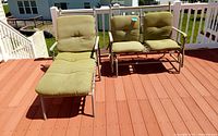 Patio furniture set on wooden deck: metal frame lounger and love seat with light green cushions
