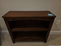 Front view of wooden bookshelf showing two shelves, dark brown wood grain finish.