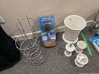 Photo showing bathroom set including Waterpik Twin Turbo shower head in packaging, ceramic cup, soap dispenser, toothbrush holder, wastebasket, and metal toilet roll holders arranged on carpet
