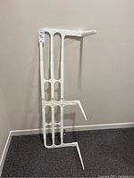 Full view of the white plastic adjustable bed rail showing the vertical slats, horizontal support bars, and under-mattress legs