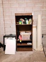 Front angled view of wood look laminate bookcase showing shelf contents and wear.