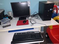 Front view of IBM ThinkVision monitor, HP Compaq desktop tower, and HP keyboard with hand rest on white desk.