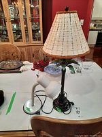 Photo showing both lamps: white gooseneck desk lamp and palm tree metal base lamp with shade on a table