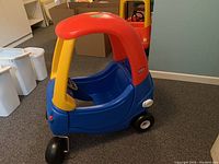 Front and side view of Little Tikes cozy coupe car showing the red roof, yellow pillars and blue plastic body with black wheels.