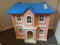 Front view of Little Tikes plastic dollhouse showing pink exterior, blue roof, and white-trimmed windows and door.