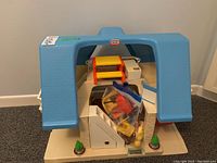 Front view of the Little Tikes playhouse with blue roof and small toy accessories bag inside.