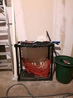 Plastic black organizer stand with slots for tool handles and red mesh pouch underneath, tools placed on top and in slots