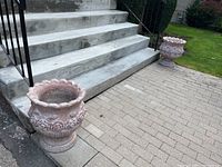 Two matching concrete planters positioned at base of concrete steps outside, showing overall size and matching appearance.