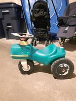 Front side view of teal Little Tikes ride on car with white front wheel and black rear wheels