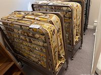 Two matching rollaway beds folded upright, showing metal frames and patterned mattresses