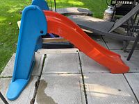 Side view of plastic slide showing blue ladder and orange slide surface.