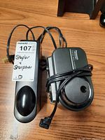 Panasonic electric pencil sharpener and Boston electric stapler with cords wound around, placed on wooden surface.