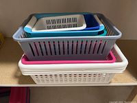 Stacked view of all plastic organizer baskets showing different sizes and colors including gray, white, pink, blue, and teal