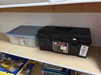 Black 19-inch plastic toolbox on shelf with storage bin beside it containing assorted hardware and tools.
