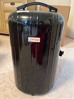 Closed view of black hard plastic Oshay wig travel case with handle and brand name plaque on front.