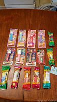 Full lot of 15 Pez dispensers arranged on a table in original packaging, depicting various character themes from early 2000s.