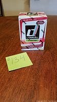 Front view of the sealed 2021-22 Donruss Soccer box sitting on wooden surface with a yellow note showing lot number #134.