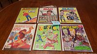 All six magazines displayed on table, showing three Mad and three Cracked magazines with colorful vintage covers.