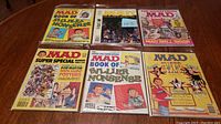 Six Mad Magazine issues arranged on a table showing colorful satirical covers from the 80s and 90s.