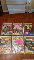 Photo showing 6 Marvel Journey Into Mystery comic books laid out on a wooden table, each in plastic sleeves.