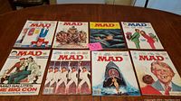 Photo showing 8 Mad Magazines from the 1970s arranged on a wooden surface with a $55 price tag visible on one issue.