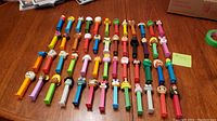 All fifty loose Pez dispensers arranged on table in rows showing variety of character heads and colors.