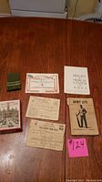Photo showing the various paper items including war ration books, Army Life booklet, certificates and a small thick booklet titled History Medical Center Area, plus a green patch folded on the table.