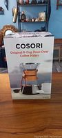 Front view of the unopened box of the Cosori Original 8-Cup Pour-Over Coffee Maker showing product image and branding.