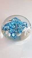 Top view of the Murano glass paperweight showing blue and white internal swirls in a circular pattern.